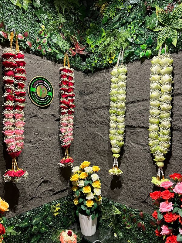Decorative floral garlands and flower bouquets on a green wall.