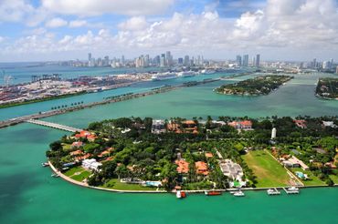 Aerial view of a coastal city with turquoise waters and cruise ships.