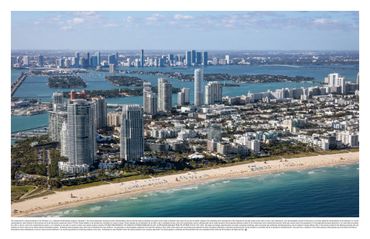 Aerial view of a coastal city with high-rise buildings and a sandy beach.
