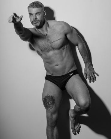 Black and white photo of a shirtless man posing dynamically.