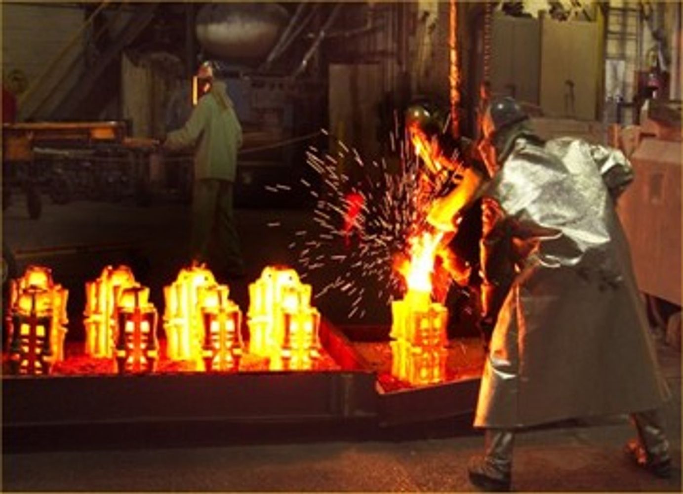 Worker pouring molten metal in foundry.