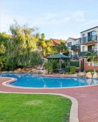 Residential pool area with greenery and a gazebo.
