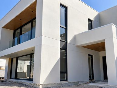 Modern two-story white house with large windows.