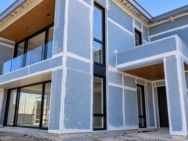 Modern house exterior under construction with blue insulation boards.