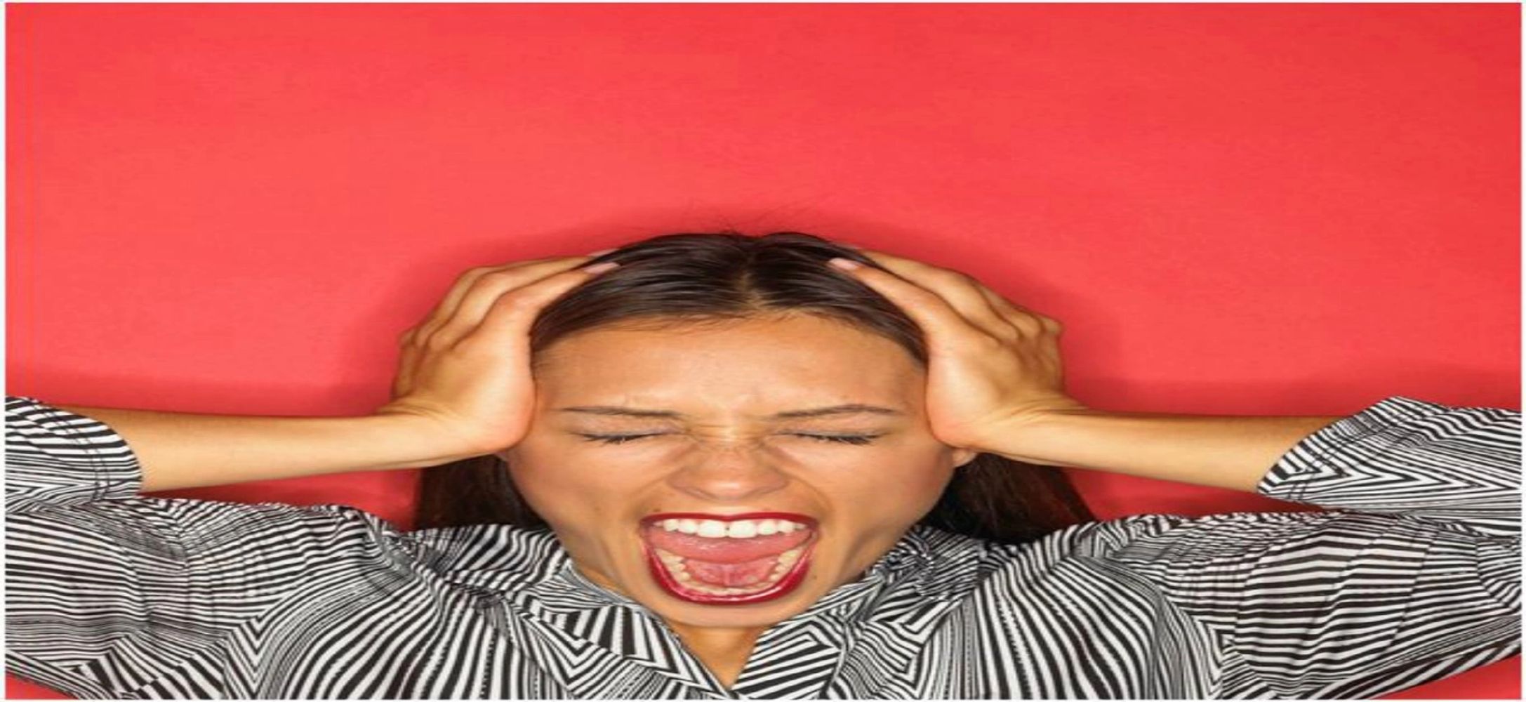 Woman with both hands pushing on the side of her head screaming in frustration.