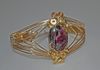Asymmetrically wrapped oval Eudalialyte cabochon mounted in round gold filled wire with the sides tapering into wraps decreasing the width of the band