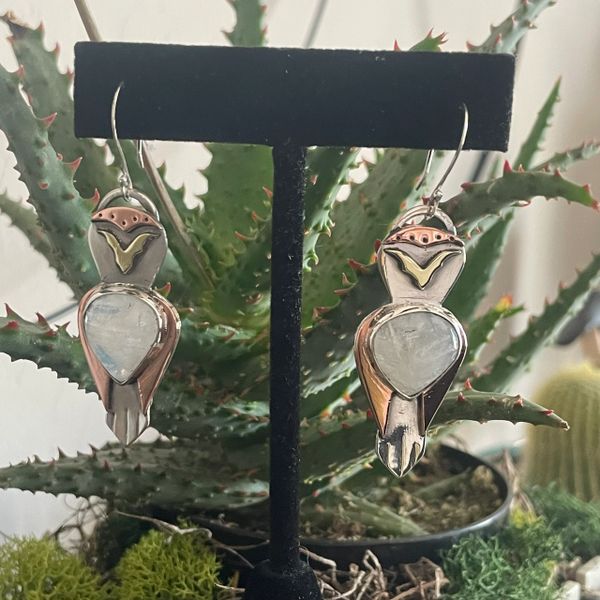 Mixed metal Owl earrings using brass, copper and sterling silver hanging on display.