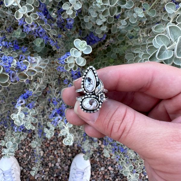 a sterling silver ring with two white buffalo stones and filagree on the side.