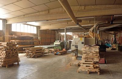 Woodworking workshop with stacked wooden planks and machinery.