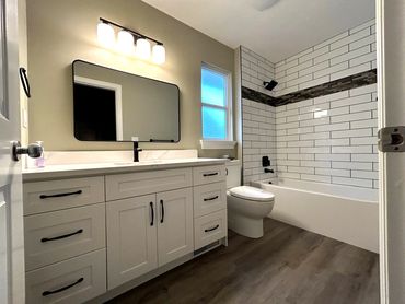 Modern bathroom with white cabinetry and tiled bathtub surround.