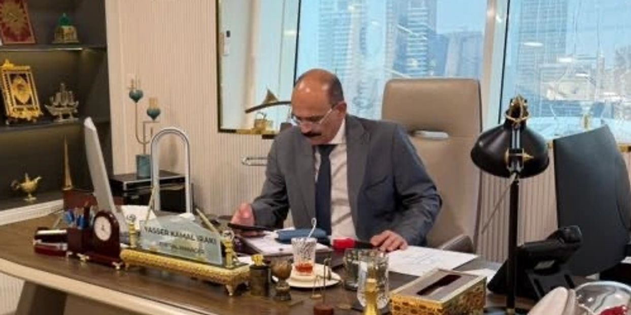 Man in suit working at a cluttered office desk.