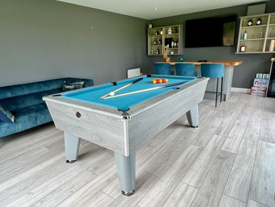 Modern game room with blue pool table and bar area.