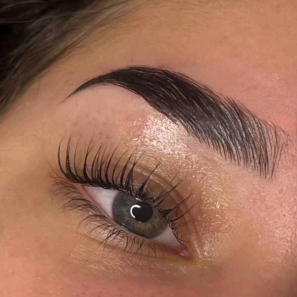 Close-up of an eye with long eyelashes and a well-groomed eyebrow.