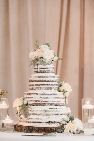 naked 4 tier wedding cake with miniature ivory roses and dusty miller