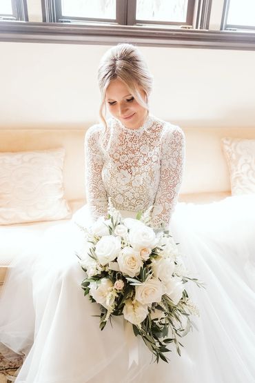 cascade bridal bouquet white roses and greenery with bride on couch