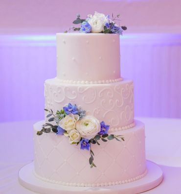  wedding cake decorated with blue delphinium rose, white ranunculus and white mini roses