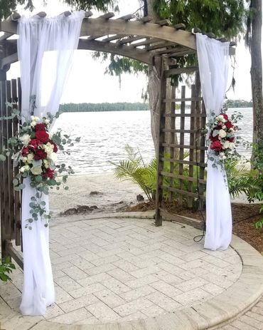 wedding ceremony arch at Paradise Cove covered with white fabric and red and white flowers