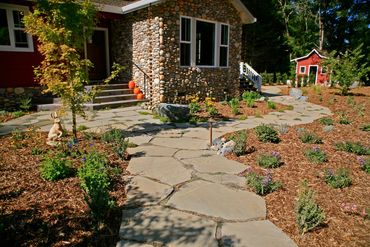 Stone house with garden and paved pathway.