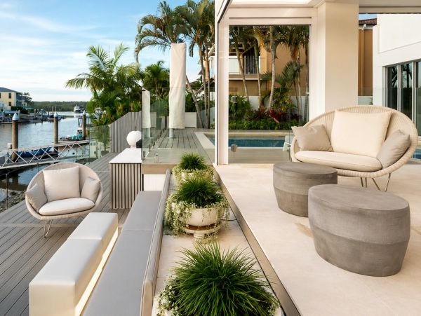 Modern outdoor seating area by waterfront with plants and chairs.