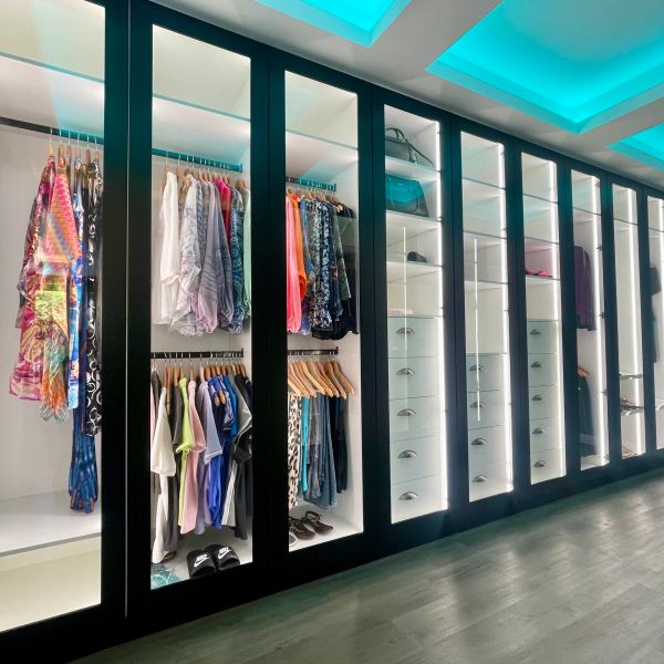 Modern illuminated wardrobe with clothes and accessories.