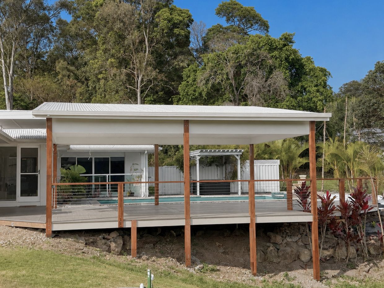 Covered patio with wooden posts by a pool.