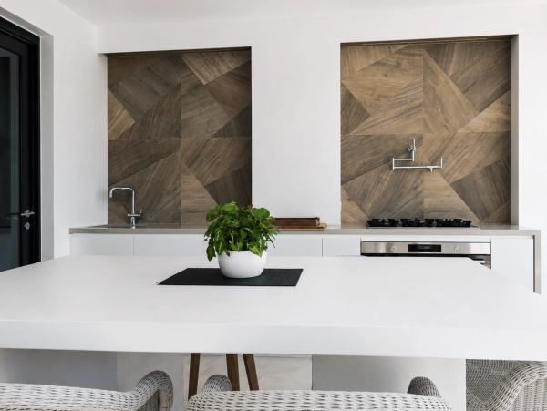 Modern kitchen with geometric wood backsplash and white countertops.