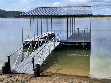 A metal dock with a roof extending into a calm lake.