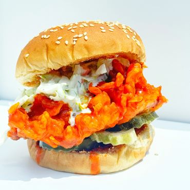 Spicy fried chicken sandwich with pickles and creamy sauce on sesame bun.