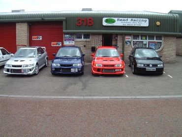Four sporty cars parked in front of Read Racing workshop with number 318.