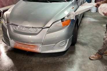 A silver car being prepared for painting in a workshop.