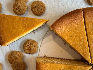Sliced pumpkin pie and round cookies on a white surface.