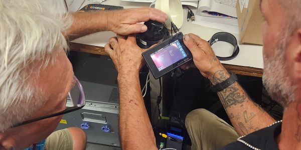 Two men examining a camera screen closely.