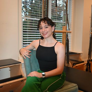 Smiling woman sitting on a chair in a fitness studio.