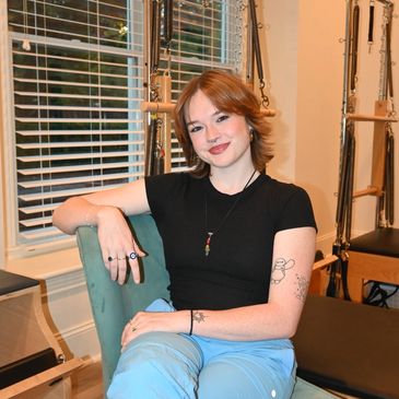 Person smiling while sitting in a chair indoors.
