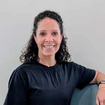 Smiling woman with curly hair in a black shirt.