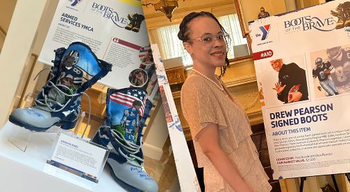 Woman posing with Drew Pearson signed boots display.