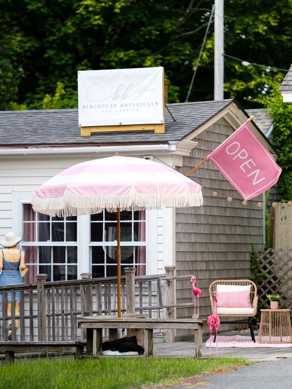 Charming storefront with pink umbrella, flamingo decorations, and an open sign.
