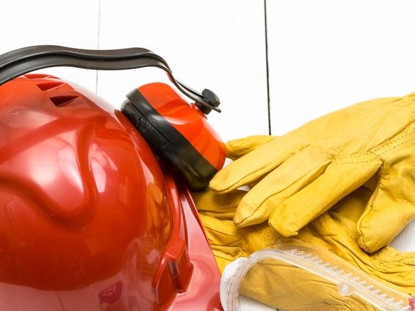 Red safety helmet, ear protection, and yellow gloves.