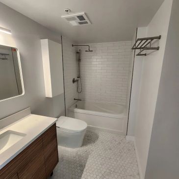 Modern bathroom with white hexagonal tiles and a wooden vanity.