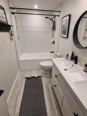 Modern bathroom with white tub, black fixtures, and a patterned rug.