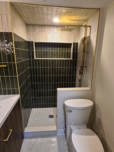 Modern bathroom with black and white tiles, gold fixtures, and a walk-in shower.