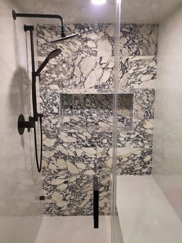 Modern shower with black fixtures and marbled tiles in a sleek bathroom.