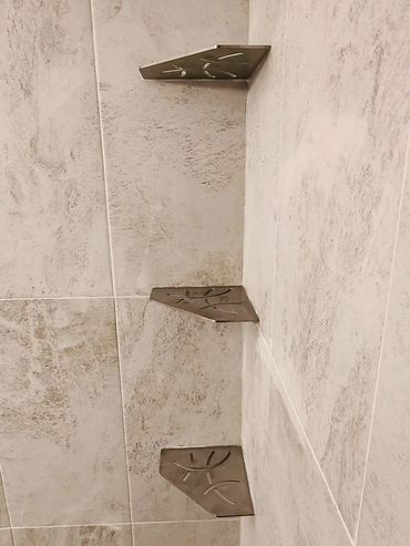 Three corner metal shelves mounted on tiled bathroom wall.