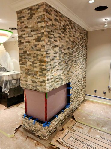 Stone fireplace installation in progress inside a home under renovation.