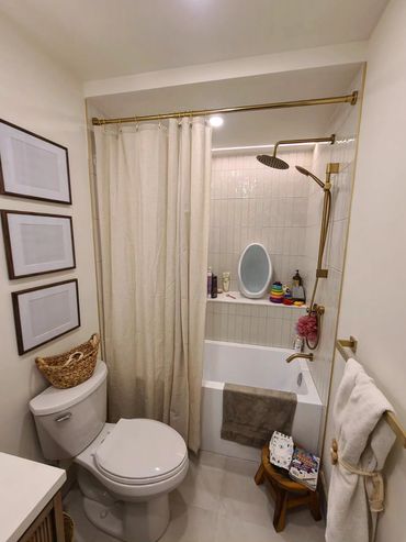 Compact bathroom with white tiles, gold fixtures, and cozy decor.