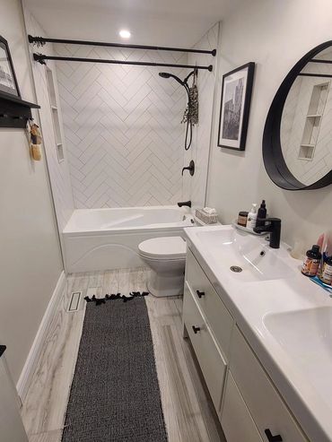 Modern bathroom with white tiles, black fixtures, and a round mirror.
