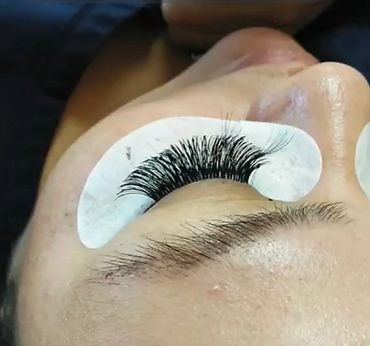 Close-up of a person getting eyelash extensions with protective pads.