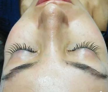 Close-up of closed eyes with long, curled eyelashes and well-groomed eyebrows.