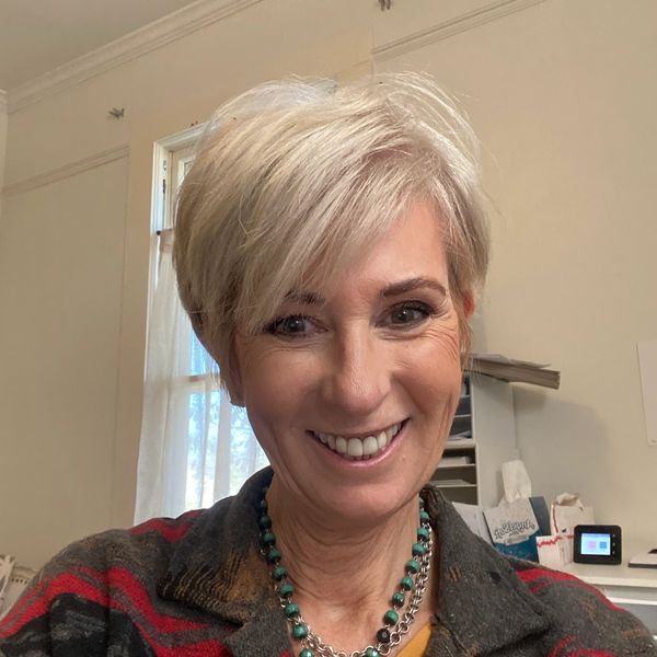 Smiling woman with short blonde hair indoors.