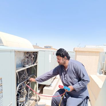 Technician repairing an air conditioning unit outdoors on a sunny day.